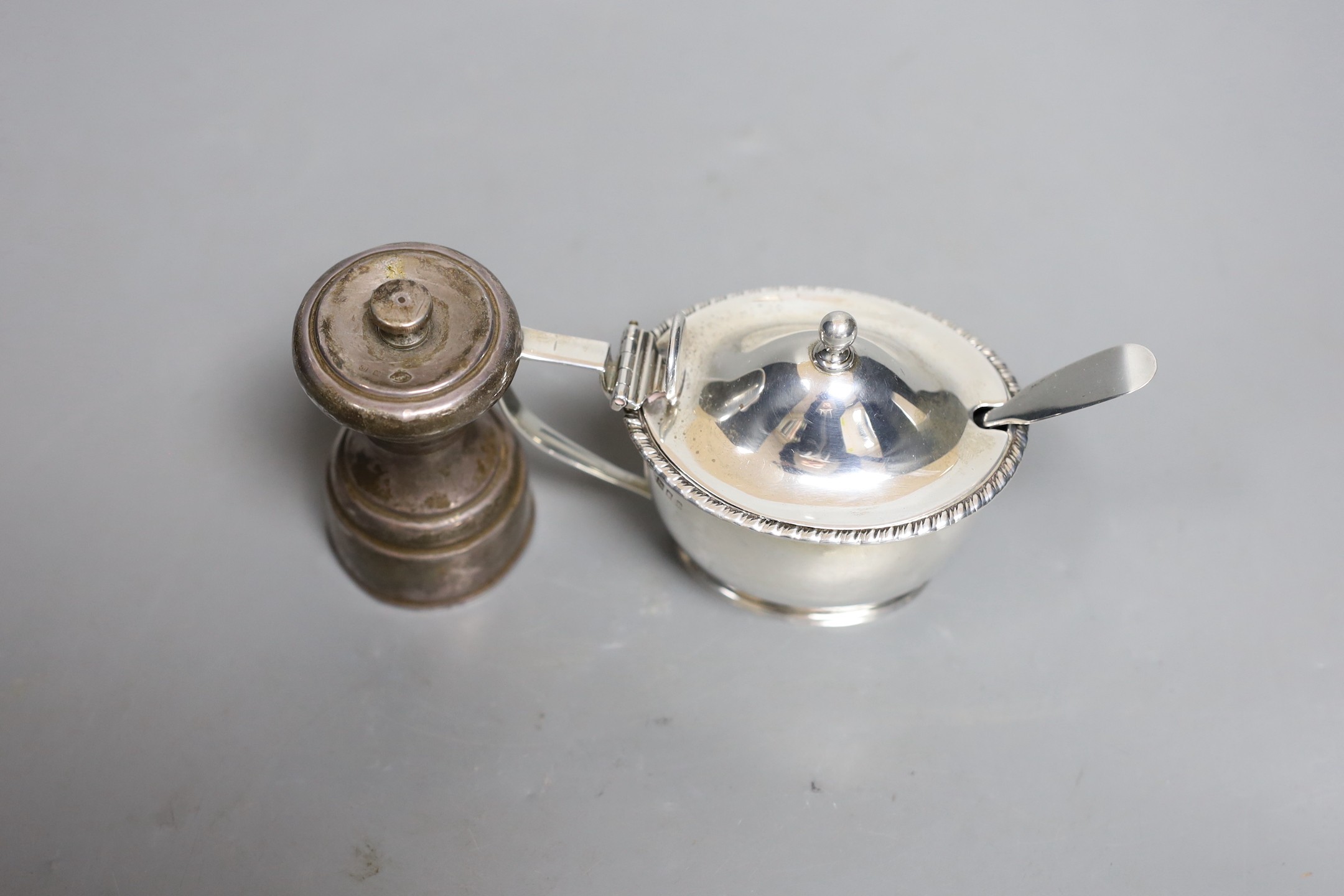 A George V silver mounted pepper mill, Birmingham, 1911, 80mm and a similar silver mustard pot.